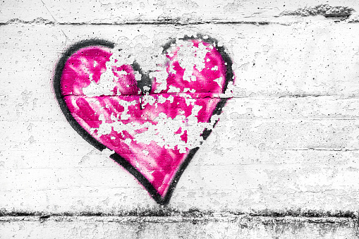 Painted pink abstract heart shape love symbol, dirty wall background, metaphor to urban and romantic valentine, grunge style.