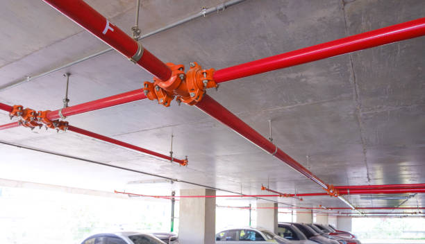 istock Red fire protective water pipeline system on concrete ceiling inside of parking garage building 1499750627