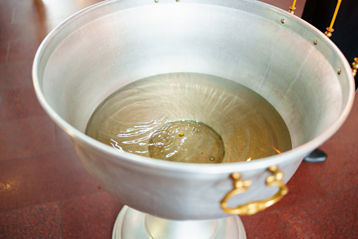 Baptismal font in the Orthodox Church. A special ritual construction. A metal bowl filled with holy water.