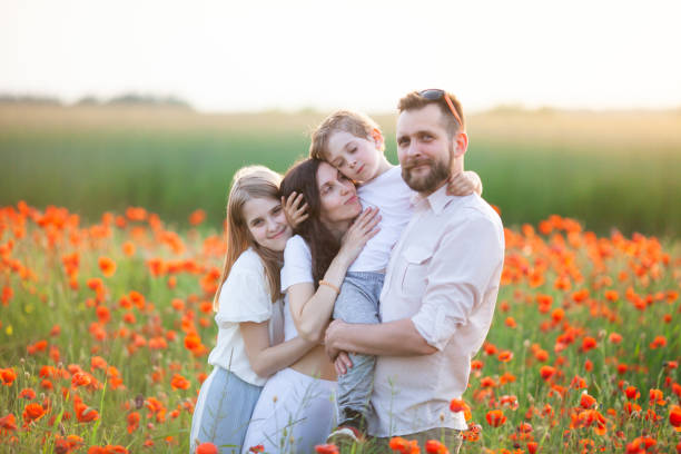 familia feliz con ropa blanca abrazándose en el campo de amapolas al amanecer. - poppy flower field red fotografías e imágenes de stock