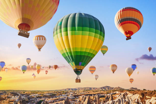 пейзаж сказочной кападокьи. красочные летающие воздушные шары в небе на восходе солнца в анатолии. отдых в красивом месте в гёреме, турция - cappadocia hot air balloon turkey basket стоковые фото и изображения