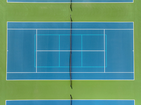Aerial photo of blue tennis courts with white lines and light blue pickleball lines