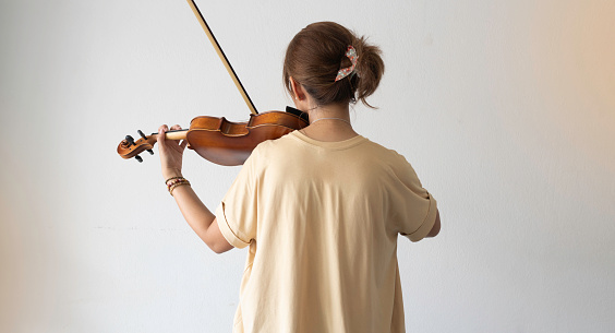 Back side of Woman holding violin and bow in hand,prepare for practice,blurry light around