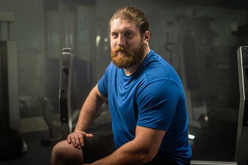 Portrait of athlete man sitting in gym.