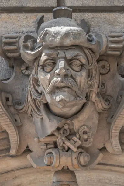 Ancient sculpture of scary, fearful and heavy armed gatekeeper, medieval warrior with weapon in historical downtown of Dresden, Germany, details, closeup. Authentic European old architecture