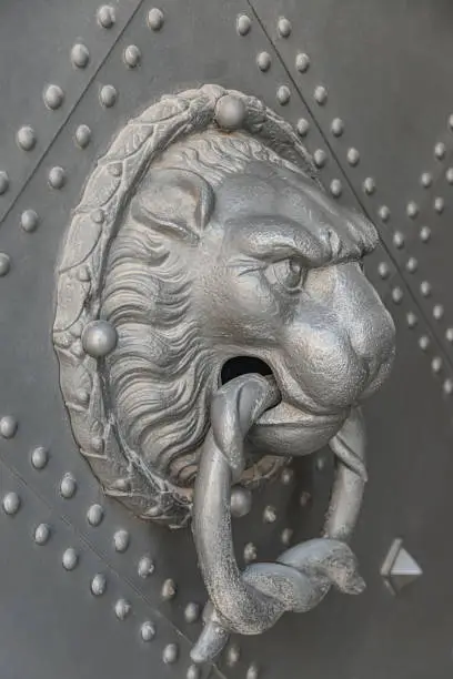 Photo of Ancient middle age iron door handle with a lion muzzle and ring, closeup, details.