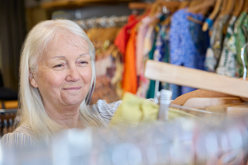 Senior Woman Buying Used Sustainable Clothes From Second Hand Charity Shop Or Thrift Store