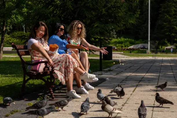 Photo of Women feeding pigeons with popcorn.