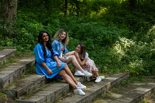 The three beautiful woman, sitting on the steps in the forest, and looking at the camera.