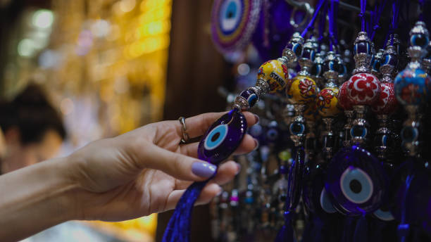 イスタンブールグランドバザールで邪眼ビーズを調べる若い観光客の女性、イスタンブールでお土産を調べる女性、邪眼に対するタリスマン、邪眼ビーズ - evil eye beads ストックフォトと画像