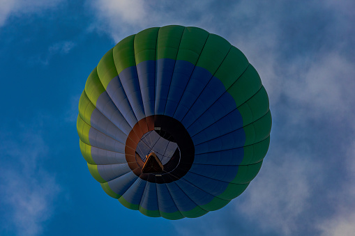 Hot air balloon landing in the middle of thicket, power lines and hills in background