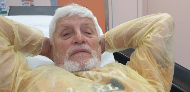 istock An elderly man with Parkinson's disease is lying down and watching the progress of percutaneous foot surgery on the screen in front of him. 1499775148
