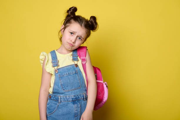 istock Little child girl, elementary school student with pink backpack, looking at camera with sad, unhappy and sorrowful gaze. 1499778607