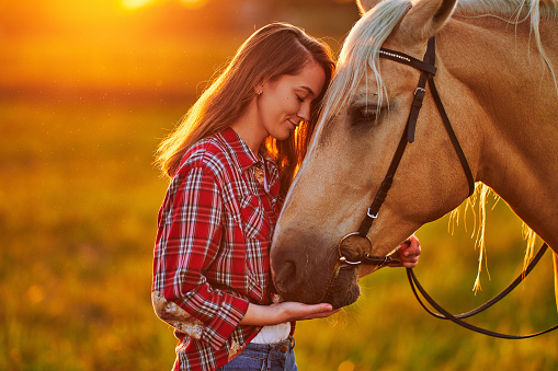 Young woman rancher walking with horse