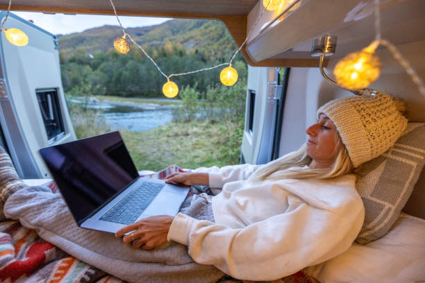 istock Woman relaxing at the back of her camper using a computer, van life concept. 1499783886
