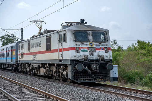 Pune, India - June 18 2023: Passenger Train hauled by a WAP7 loco heads towards Pune, at Uruli near Pune India.