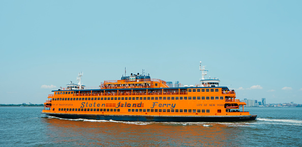 New York City, United States - May 22, 2023: A ferryboat of the Staten Island Ferry browses by the New York Bay, United States, on a sunny spring day