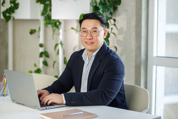 istock Smiling asian businessman working, using laptop. Human resources. Finance concept. Multiracial 1499794147