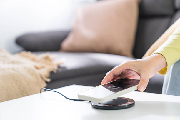 istock Woman hands plugging a charger in a smart phone. Charging Smartphone with Wireless Charging Pad at Home 1499794344