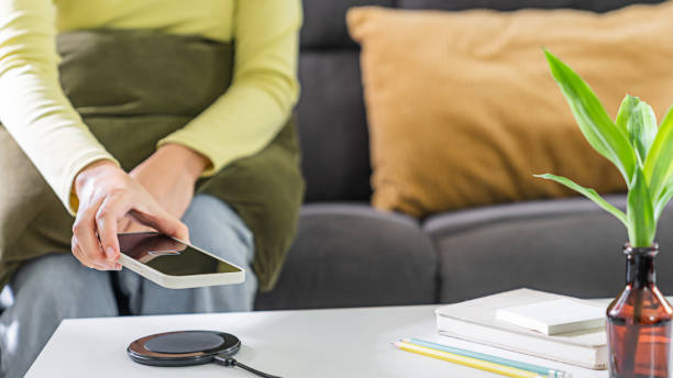 istock Woman hands plugging a charger in a smart phone. Charging Smartphone with Wireless Charging Pad at Home 1499794351