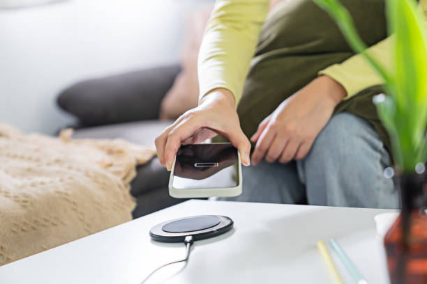 istock Woman hands plugging a charger in a smart phone. Charging Smartphone with Wireless Charging Pad at Home 1499794352