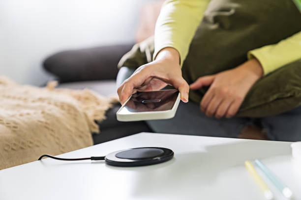istock Woman hands plugging a charger in a smart phone. Charging Smartphone with Wireless Charging Pad at Home 1499794356