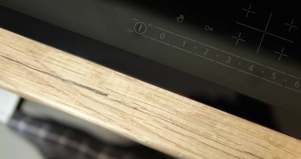istock Top view turned off control panel black induction cooktop on wooden countertop. Close up shot of modern electrical hob with touch buttons. 1499795487