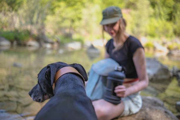 Young woman hydrating and having fun with her dog by the river