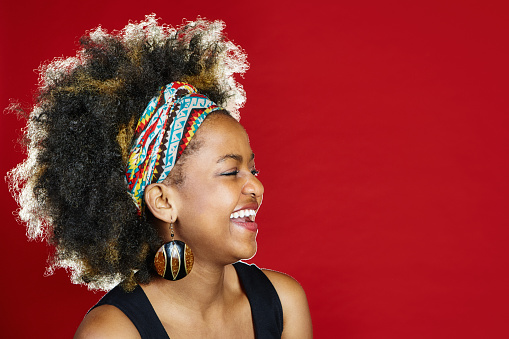 Young woman with multi-colored hairband and natural black hair looks happy and relaxed.