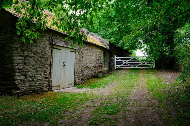 Stone barn with footpath leading to a white wooden gate concept of peacefulness and relaxation away from crowds of people