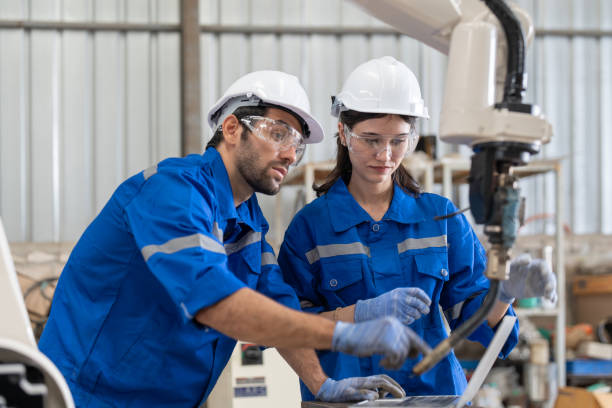 istock Male and female engineer using laptop working with robot arm welding machine in industrial factory. Team of technician automation robot in uniform explains robot arm system. 1499798722