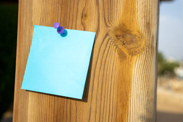 purple map pin and blue square paper note on a natural orange piece of wood with empty free space for template or blank copy area