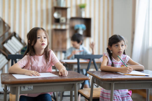 istock Cute little girl using color pencil drawing on paper in art study class at elementary school. Group diverse student to listen teacher in classroom . Children education and learning concept. 1499800063