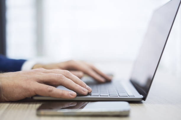 istock The image presents a man's hands up close as they navigate a modern laptop's keyboard, against a blurred office scene 1499801696