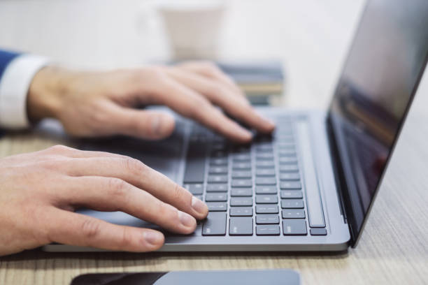 istock Set against a blurry office setting, a close-up reveals a man's hands typing on a sleek laptop keyboard 1499801714
