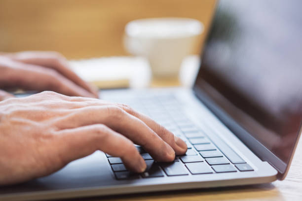 istock With an office backdrop appearing blurry, a close-up presents a man's hands typing on a state-of-the-art laptop keyboard 1499802247