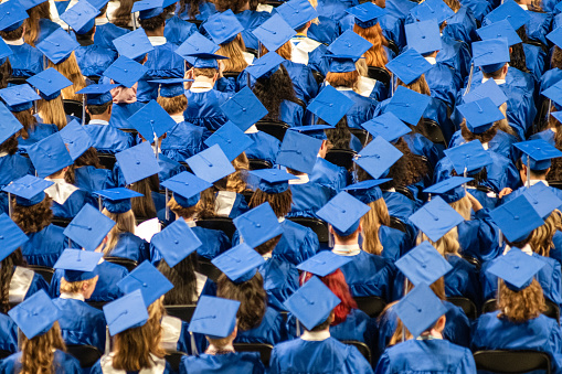 Student audience wearing grown and mortarboard hats during High School Graduation Ceremony