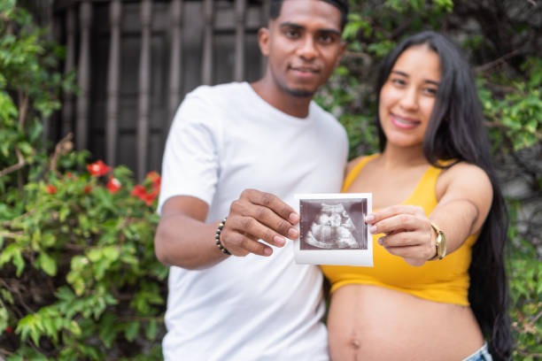 Young couple showing baby's ultrasound results Young couple showing baby's ultrasound results, standing outdoors first ultrasound stock pictures, royalty-free photos & images