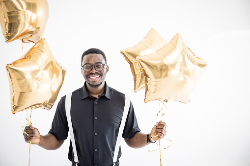 Portrait of a happy guy holding balloons and celebrating.