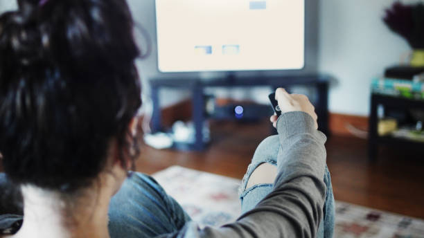 istock Woman with a remote control watching tv at home 1499809378