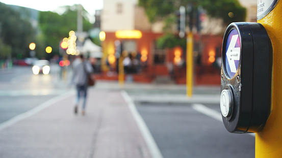 Push Button and Crossing sign for pedestrian crosswalk on a yellow post along the city street