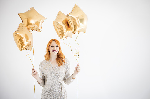 Happy woman feeling festive while holding balloons and dancing. Studio shot