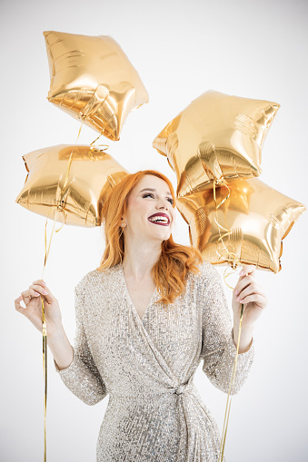 Happy woman feeling festive while holding balloons and dancing. Studio shot