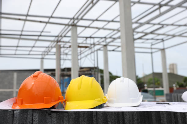 Orange Yellow and White Safety hard hat on blueprint drawing at construction site, Concept of construction and design. Engineering tools blueprints and walkie-talkie, white , orange, and yellow helmet, construction drawing, Construction worker supplies casco de seguridad amarillo y blanco naranja en el plano de dibujo en el sitio de construcción, concepto de construcción y diseño. planos de herramientas de ingeniería y walkie-talkie, casco blanco, naranja y amarillo, dibujo de construcción, suminist
