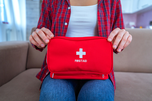 Woman holds medical first aid kit with medicine and pills for pain and illness at home