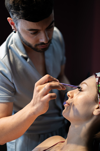 Professional artist applying makeup on model face.