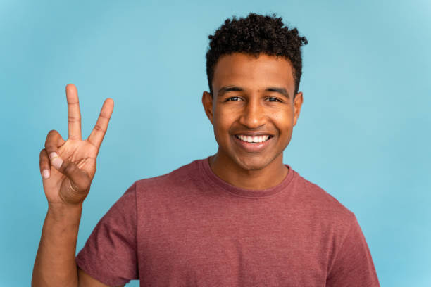 istock Smiling young man making peace sign with fingers. 1499823995