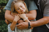 Little Girl Being Hugged by Parents