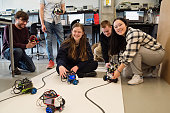 Diverse team of college students and professor in robotics classroom.