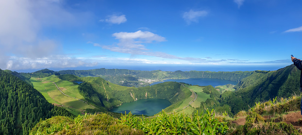 Hiker, visible just hand holding mobile phone, at the caldera on São Miguel island in the Azores